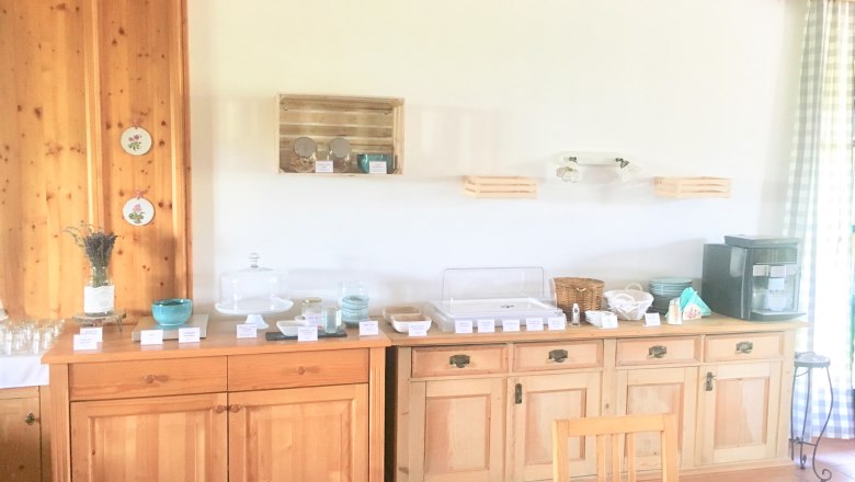 Frühstücksbuffet, © Fam. Ritz Frühstücksbuffet auf einem Holzbuffet mit Geschirr, Gläsern und einer Kaffeemaschine.