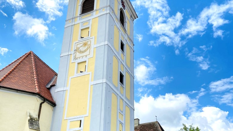 Schiefer Turm von Waitzendorf, © Weinstraße Weinviertel Schiefer Turm in Waitzendorf mit gelber Fassade und Uhr, umgeben von blauen Himmel und Wolken.