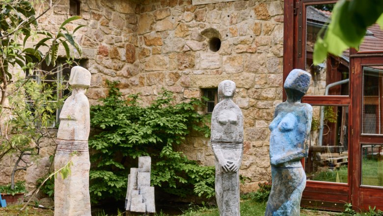 Gut Gasteil, © Nina Nagy Photography Drei bunte Skulpturen stehen auf einer Wiese vor einem alten Steingebäude