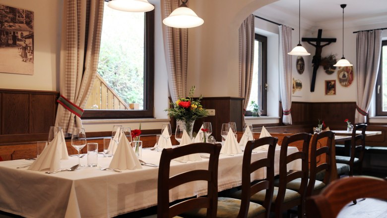 Innenraum im Waldgasthof Steinbründl, © Familie Kogler-Renner Innenraum eines gemütlichen Gasthofs mit gedecktem Tisch, Holzmöbeln und Dekorationen an den Wänden.