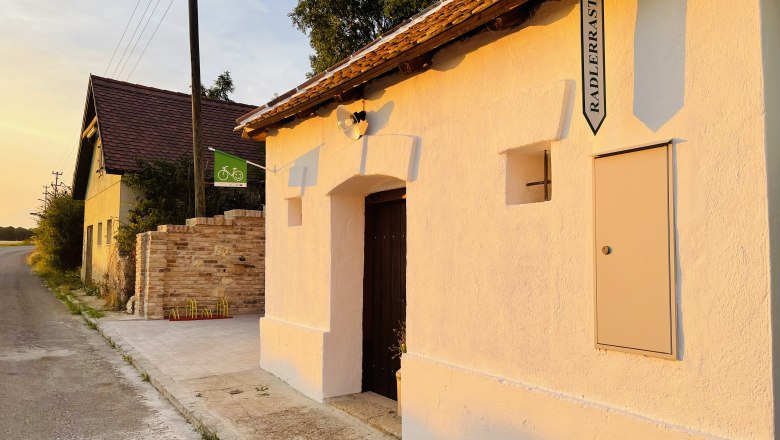 Keller außen, © Fam. Thürr Außenansicht eines Kellers mit Schild 'Radlerrast' bei Sonnenuntergang.