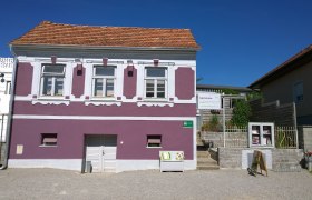 Außenansicht, © Fam. Winkler Außenansicht eines lila Hauses mit weißen Fensterrahmen und einem Schild für ein Gästehaus.