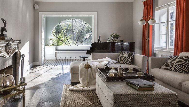 Villa Antoinette, © Matthias Kronfuss Elegantes Wohnzimmer mit Kamin, Klavier und großen Fenstern.