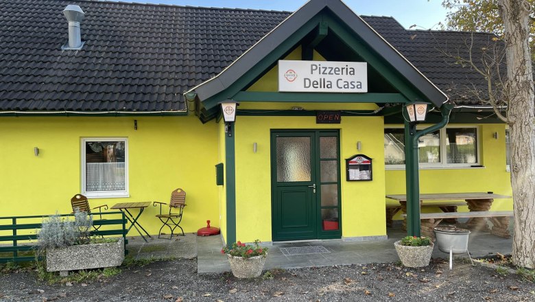 Pizzeria Della Casa, © Pizzeria Della Casa Außenansicht einer gelben Pizzeria mit dem Namen 'Pizzeria Della Casa'.