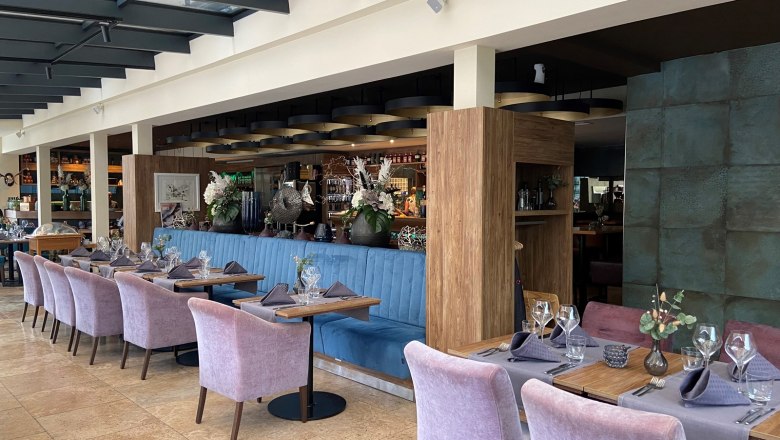 Gut essen im Bevanda, © Wiener Alpen Elegantes Restaurant mit gedeckten Tischen und lila Stühlen.