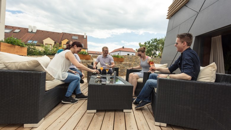 Geselligkeit auf der Terrasse, © KASTNER NEW MEDIA - kastner.tv Gruppe von Menschen sitzt auf einer Terrasse und genießt Getränke.