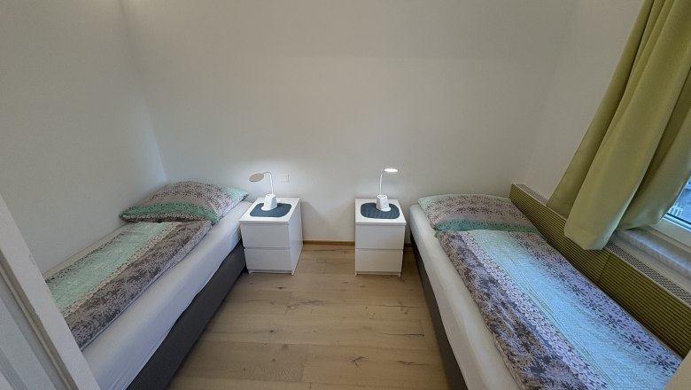 TDR-Haus Morgensonne Schlafzimmer, © Fam Pauker Schlafzimmer mit zwei Einzelbetten, Nachttisch und Lampen.