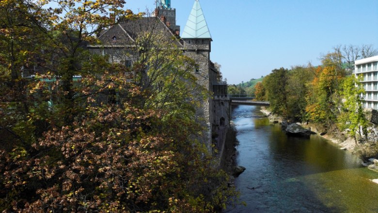 Herbststimmung, © Natur im Garten/Alexander Haiden Fluss mit Herbstbäumen und Gebäude im Hintergrund.