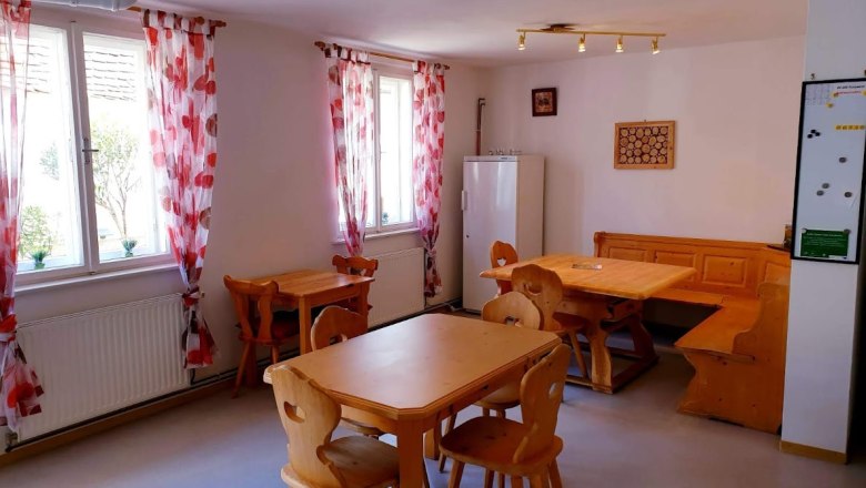 Weingut Krell, © Weingut Krell Gemütlicher Raum mit Holzmöbeln und roten Vorhängen.