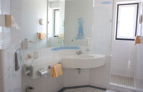 Seminarhotel - Raststation Göttlesbrunn, © Autogrill Austria AG Helles Badezimmer mit Waschbecken, Spiegel, Dusche und Handtüchern.