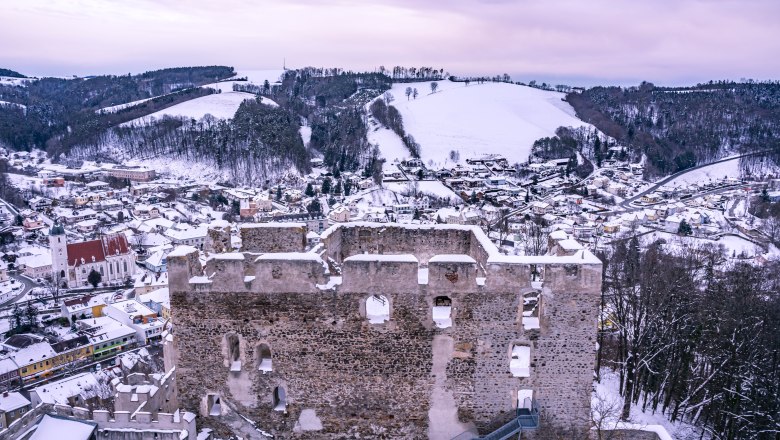 Ausblick vom Feuerturm der Burgruine Kirchschlag, © Wiener Alpen, Flotoanker - Luckerbauer Winterliche Ansicht der Burgruine Kirchschlag mit verschneiter Landschaft im Hintergrund.