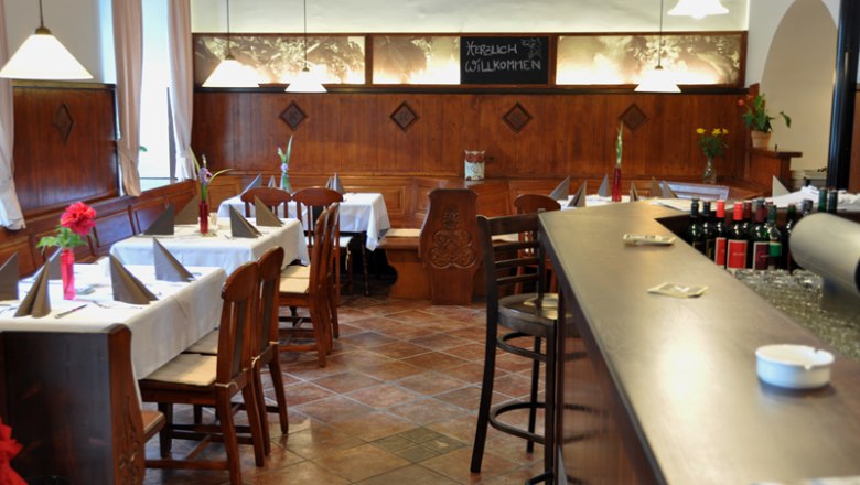 Innenansicht vom Melker Stadtheurige, © Koloman - Der Melker Stadtheurige Innenansicht eines gemütlichen Restaurants mit Holzmöbeln und gedeckten Tischen.