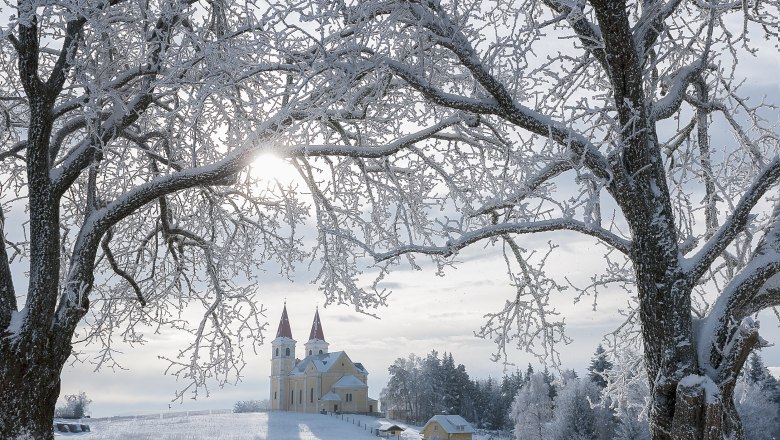 Wallfahrtskirche Maria Schnee, © Wiener Alpen, Foto: Walter Strobl Winterlandschaft mit Wallfahrtskirche Maria Schnee im Hintergrund, umrahmt von schneebedeckten Bäumen.