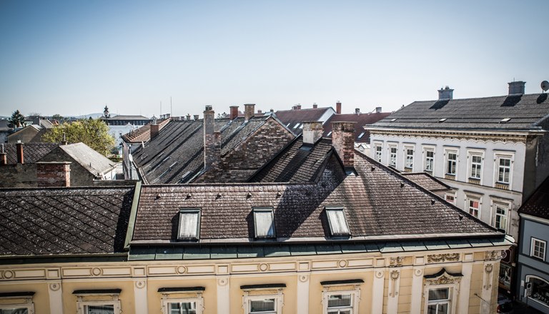 Zimmer Ausblick, © flotographix Ausblick auf Dächer der Nachbargebäude und blauem Himmel.