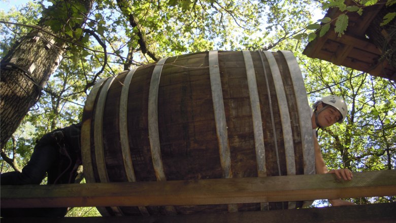 Natur erleben und entspannen, © Gemeinde Kreuzstetten Person mit Helm kriecht durch ein großes Holzfass in einem Kletterpark.