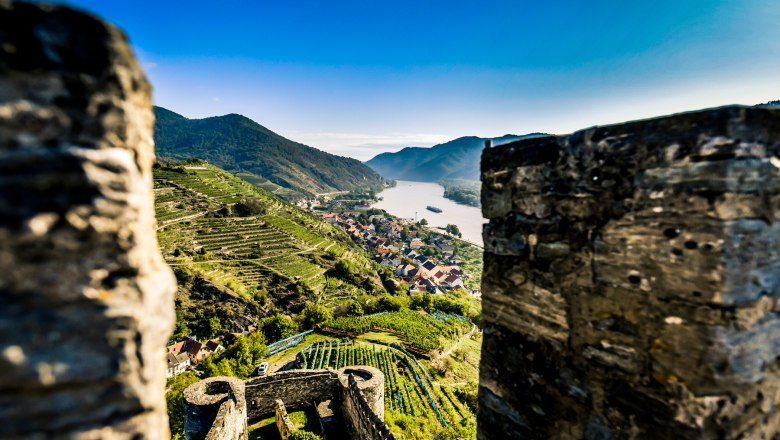 Ausblick von der Ruine Hinterhaus, © Robert Herbst Blick von einer Burgruine auf eine Flusslandschaft mit Weinbergen und einem Dorf.