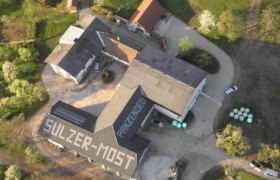 Sulzermost, © zVg Luftaufnahme eines Gebäudekomplexes mit der Aufschrift 'Sulzer-Most' auf dem Dach.