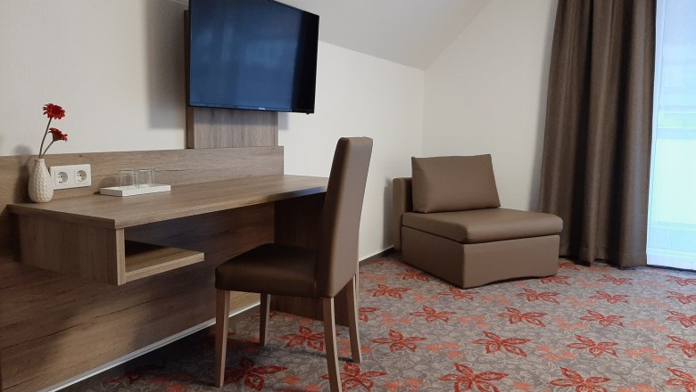 Doppelzimmer, © Gerhard Auer Hotelzimmer mit Schreibtisch, Stuhl, Fernseher und Sessel.