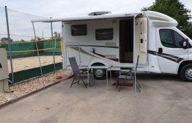 Wohnmobilstellplatz, © Gemeinde Ebenthal Wohnmobil mit ausgefahrener Markise und Campingmöbeln auf einem Stellplatz neben einem Volleyballfeld.