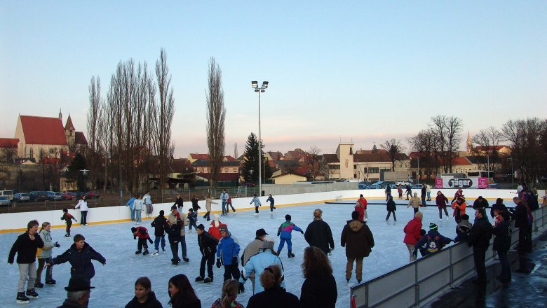 Eislaufplatz in Eggenburg, © Donner Karl Menschen beim Eislaufen auf einem Freiluft-Eislaufplatz mit einer Kirche im Hintergrund.