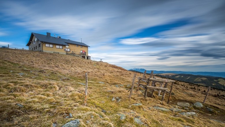 Wetterkoglerhaus am Hochwechsel, © Wiener Alpen, Christian Kremsl Berghütte auf einem Hügel mit bewölktem Himmel im Hintergrund.