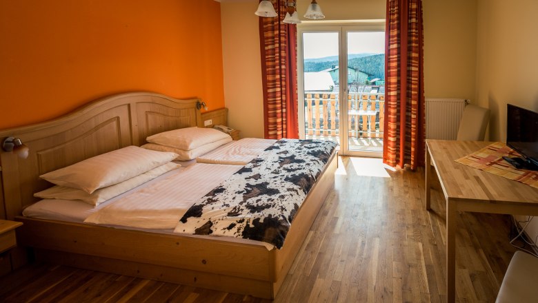 Sonnenhof, © Wiener Alpen / Christian Kremsl Gemütliches Hotelzimmer mit Doppelbett, Holzmöbeln und Balkon mit Ausblick.