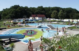 Parkbad Bruck/Leitha, © Wolfgang Stinauer Freibad mit mehreren Becken, Rutsche und Liegewiese, umgeben von Bäumen.