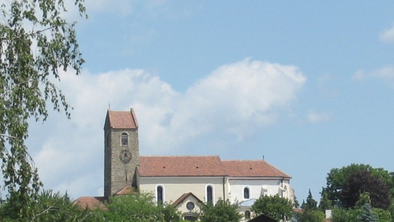 Hohenwarth, © Gemeinde Hohenwarth-Mühlbach a.M. Kirche mit Turm und rotem Dach in Hohenwarth, umgeben von Bäumen und blauem Himmel.
