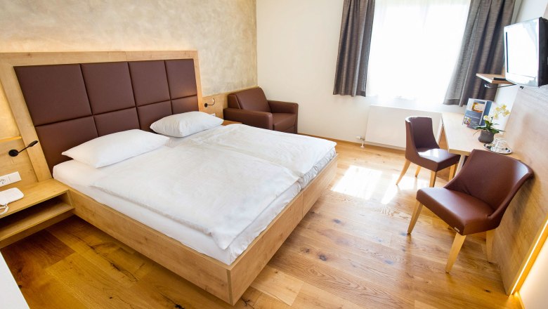 Zimmeransicht, © Hotel Stich Modern eingerichtetes Hotelzimmer mit Doppelbett, Schreibtisch, Stühlen und einem Sessel.