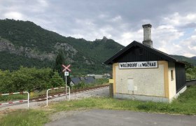 Bahnhof Willendorf, © Donau NÖ Tourismus Kleines Bahnhofsgebäude in Willendorf in der Wachau, umgeben von grünen Hügeln und Bahngleisen.