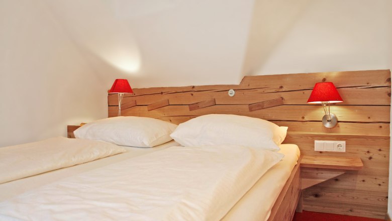 Gästezimmer Weingut Polz, © Weingut Polz Gästezimmer mit Holzbett und roten Lampen.
