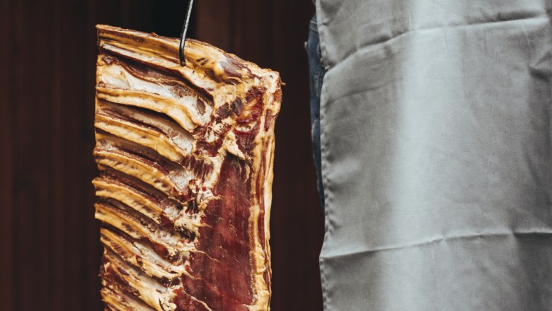 Fleisch aus eigener Schlachtung, © Niederösterreich Werbung/David Schreiber Person hält ein großes Stück Fleisch mit Rippen an einem Haken.