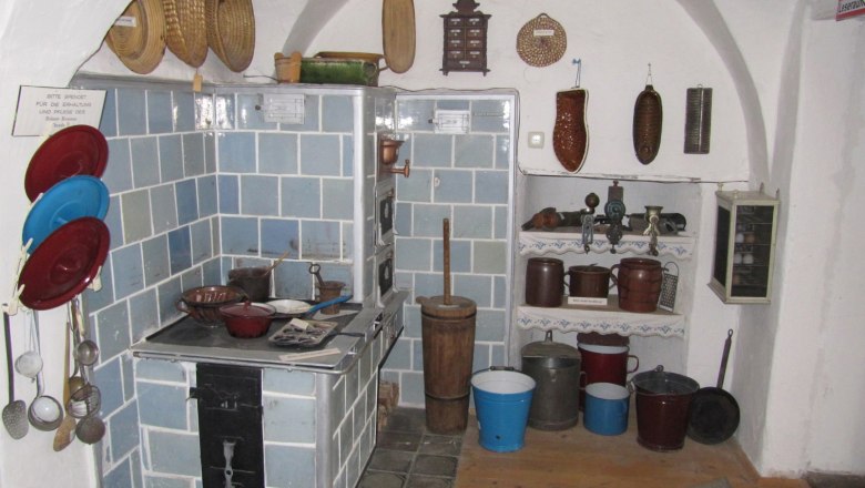 Südmährermuseum, © Südmährermuseum Historische Küche im Südmährermuseum mit blau gekacheltem Ofen und traditionellen Küchenutensilien.