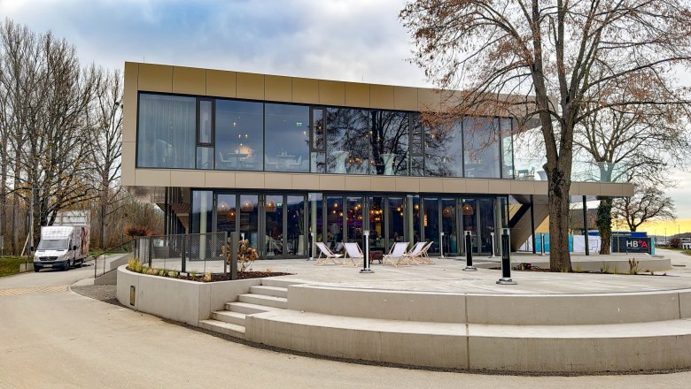 Aussenansicht Mole Melk, © Mole Melk Moderne zweistöckige Gebäude mit Glasfassade und Terrasse, umgeben von Bäumen.