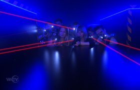 Lasertag, © Suracon OG Menschen spielen Lasertag in einem dunklen Raum mit blauen Lichtern und roten Laserstrahlen.