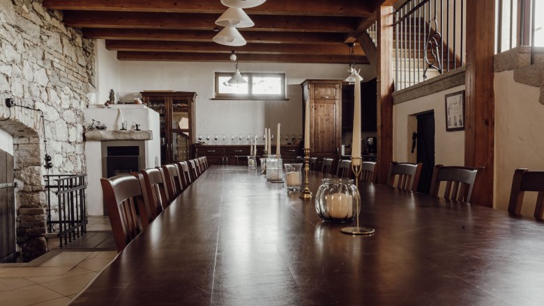 Untergeschoss mit Kaminofen, © Weinakademie Retz Großer Raum mit langem Holztisch, Kaminofen und Steinwand.