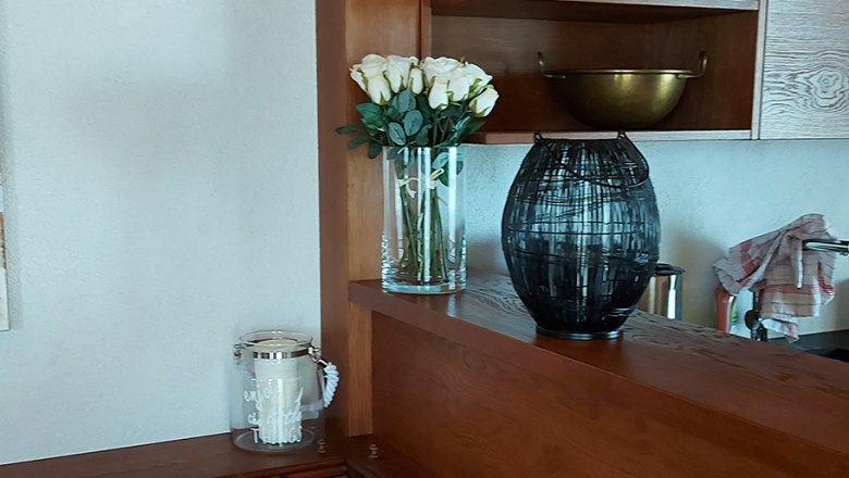 Küche, © Bernadette Gierlinger Holzküche mit Regalen, Kissen und Dekorationen.