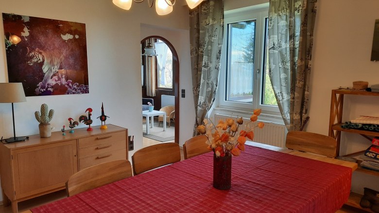 2. Obergeschoss Esszimmer, © Dr. Eva Dirnbacher Esszimmer mit rotem Tischläufer, Holzmöbeln und Tigerbild an der Wand.
