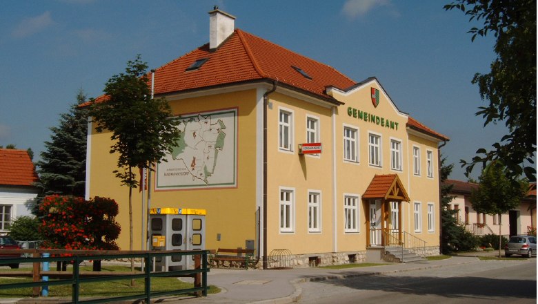 Gemeindeamt, © Gemeinde Harmannsdorf-Rückersdorf Ein gelbes Gebäude mit der Aufschrift 'Gemeindeamt', einem Wappen und einer Karte an der Wand.