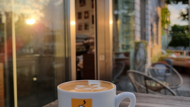 TDR-Kaffeetasse Egon to Go, © Yana Tereshchenko Sonnenaufgang, Gastgarten Tasse Kaffee auf Tisch