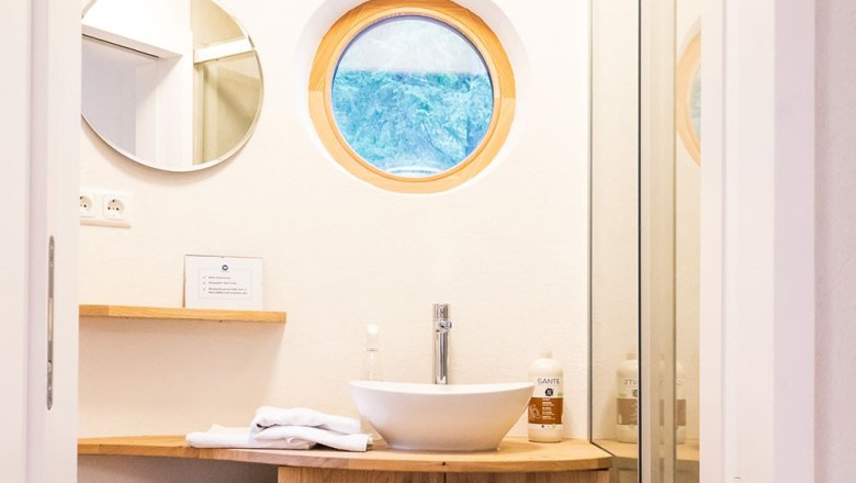 Badezimmer Luna, © WW Wohnwagon GmbH Modernes Badezimmer mit rundem Fenster und Waschbecken.