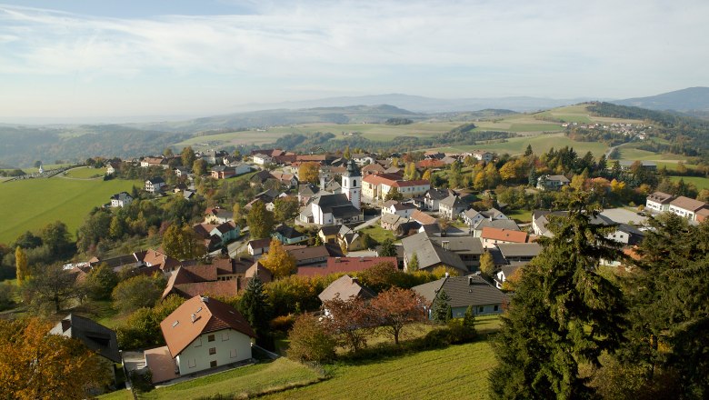 Hochneukirchen-Gschaidt, © MG Hochneukirchen-Gschaidt, Foto Franz Zwickl Luftaufnahme von Hochneukirchen-Gschaidt mit Häusern, Kirche und grüner Landschaft.
