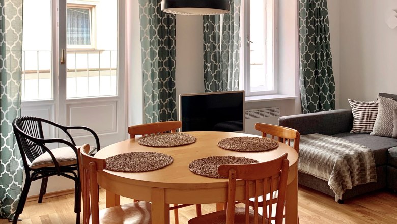 Wohnbereich - Superior Apartment Top 6, © VP FeWo OG Wohnzimmer mit Esstisch, Stühlen, Sofa und Vorhängen.