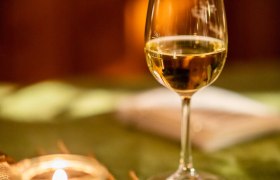 Bergadvent Rax, Advent, Raxalm-Bergstation, Winter, Rax-Seilbahn, Region Semmering-Rax, Wiener Alpen in Niederösterreich, © Wiener Alpen/Christian Kremsl Ein Glas Weißwein mit einer Kerze auf einem Tisch mit grünem Tischtuch.