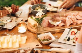 Heurigenjause, © NÖ Werbung / Julius Hirtzberger Ein gedeckter Tisch mit Brot, Käse, Aufschnitt und Weingläsern.