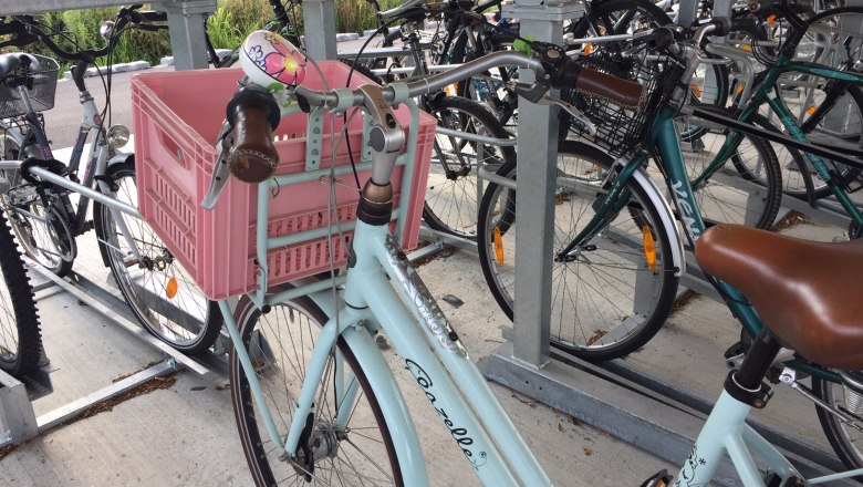 Radradreparatur, © Donau Niederösterreich Tourismus, Lydia Hölterer Fahrrad mit rosa Kiste in einem Fahrradständer.