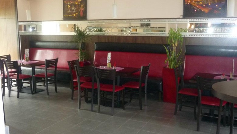 Café Bar Atlantis, Enzersdorf/Fischa, © Semir Koro Innenansicht eines Cafés mit roten Sitzbänken und schwarzen Stühlen.