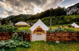 Glamping Wildnis Zentrum Nasswald, © Jonathan Clark Glamping-Zelt in grüner Landschaft mit Bergen im Hintergrund.