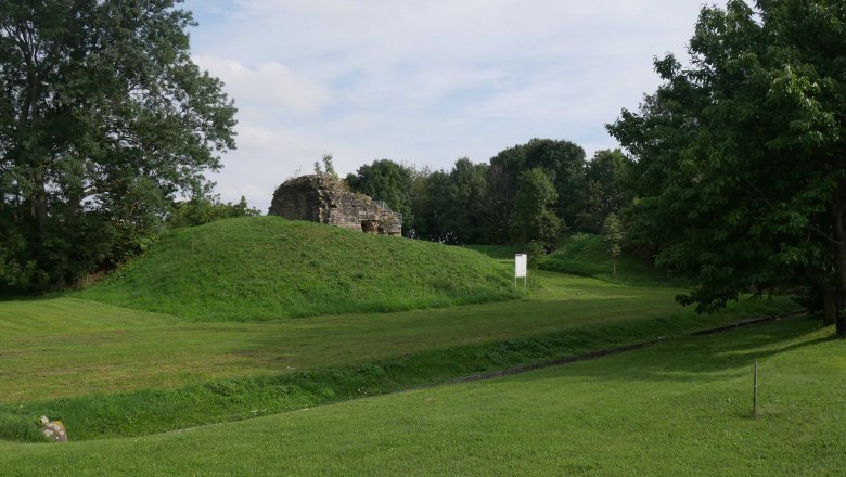 Burg Sachsendorf, © ARDIG Ruine der Burg Sachsendorf auf einem grasbewachsenen Hügel, umgeben von Bäumen.