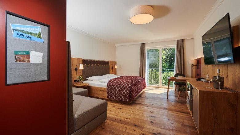 RelaxResort Kothmühle, © Dominik Stixenberger Hotelzimmer mit Doppelbett, Holzboden, Balkon und Fernseher.